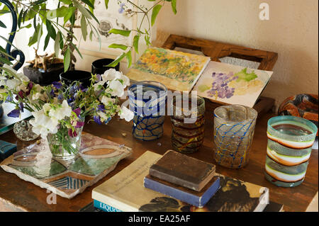 Reihe von Glas Tassen auf Tischplatte mit kleinen Aquarelle und Sweet Pea Blumenvase. Stockfoto