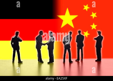 Modellfiguren als Symbol für Politiker stehen die Flaggen von China und Deutschland. Zwei von ihnen die Hand. Stockfoto