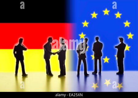 Modellfiguren als Symbol für Politiker stehen die Flaggen von Europa und Deutschland. Zwei von ihnen die Hand. Stockfoto