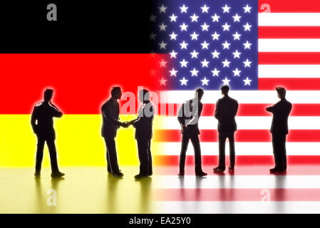 Modellfiguren als Symbol für Politiker stehen die Fahnen der USA und Deutschland. Zwei von ihnen die Hand. Stockfoto