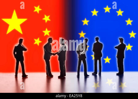 Modellfiguren als Symbol für Politiker stehen die Flaggen von China und der EU. Zwei von ihnen die Hand. Stockfoto