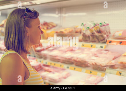 Junge Frau Wahl Fleisch im Supermarkt. Stockfoto