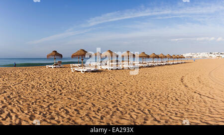 Strand mit leeren Sonnenliegen in die Stadt Albufeira bei Sonnenuntergang. Algarve. Süd-Portugal. Stockfoto