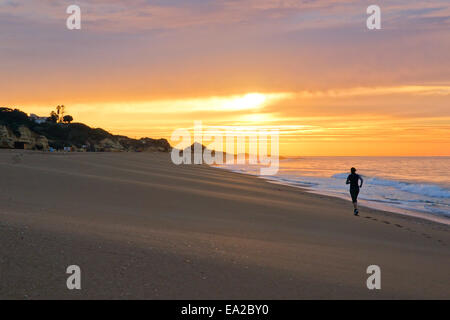 Frau, jogging am Strand entlang dem Meer von Albufeira bei Sonnenuntergang. Portugal. Stockfoto