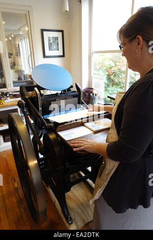 USA Maryland MD Chestertown a woman uses a vintage letterpress machine printing press Stockfoto