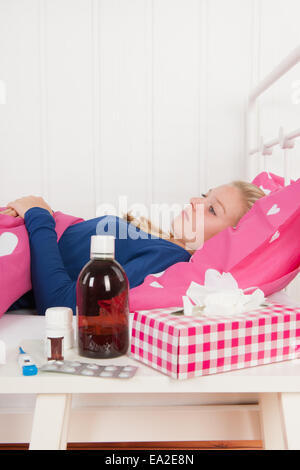 Kranke Teen Mädchen mit im Bett mit der Medizin vor (Schwerpunkt Mädchen) Stockfoto