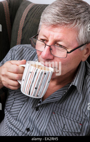 Entspannte Erwachsene Mann Kaffeetrinken zu Hause sitzen auf couch Stockfoto