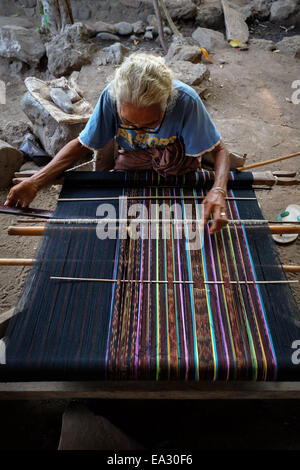 Eine Frau, die in ihrer Werkstatt webt - eine traditionelle, alternative Einkommensquelle im Dorf Lamagute, Lembata, Indonesien. Stockfoto