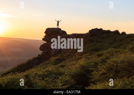 Am Anfang der Welt genießt der Besucher Sonnenuntergang am Curbar Rand mit Armen empor, Peak District National Park, Derbyshire, England, UK Stockfoto