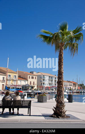 Frauen auf einer Bank in der Nähe von einer Palme auf dem Kai von Meze Hafen, Herault, Languedoc-Roussillon Region, Frankreich, Europa Stockfoto