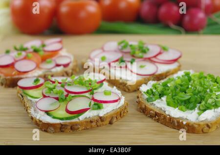 vier Scheiben Brot mit Quark und Gemüse Stockfoto