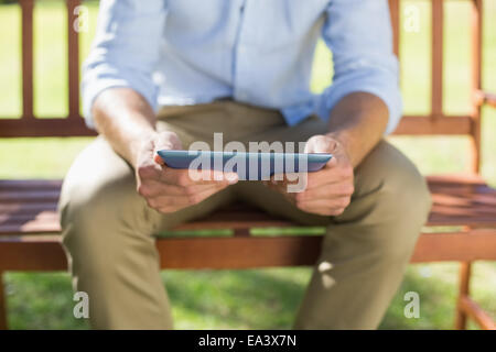 Mann sitzt auf der Parkbank mit tablet Stockfoto