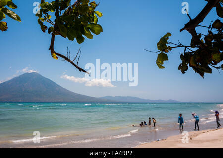 Menschen, die Freizeit an einem Strand mit Blick auf die Boleng-Straße und den Berg Boleng (Adonara-Insel) haben; fotografiert auf der Insel Lembata, Indonesien. Stockfoto