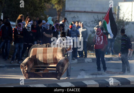 Ramallah, Westjordanland, Palästinensische Gebiete. 7. November 2014. Eine palästinensische Studenten der BirZeit Universität drückt ein Sofa bei Zusammenstößen mit israelischen Sicherheitskräften nach einer Anti-Israel-Demonstration über die aktuellen Einschränkungen bei der Einreise in die al-Aqsa-Moschee, außerhalb Israels Ofer Militärgefängnis in der Nähe von der Westbank Ramallah 6. November 2014. Hochspannung herrschte in der West Bank und Ostjerusalem nach zwei Lauf über Angriffe durch Palästinenser Treiber gegen israelische Soldaten im Jerusalem und Hebron, verursacht den Tod eines israelischen Grenze Polizisten und verletzt Stockfoto