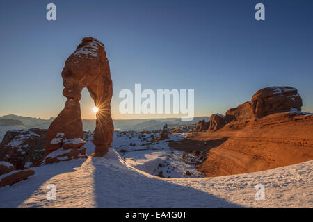 Abendsonne scheint durch Delicate Arch, Arches-Nationalpark; Utah, Vereinigte Staaten von Amerika Stockfoto