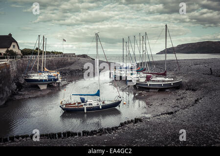 Segelboote Rest sanft auf Sand, Schlamm und Felsen bei Ebbe im kleinen Hafen von Porlock Weir, Somerset. Stockfoto