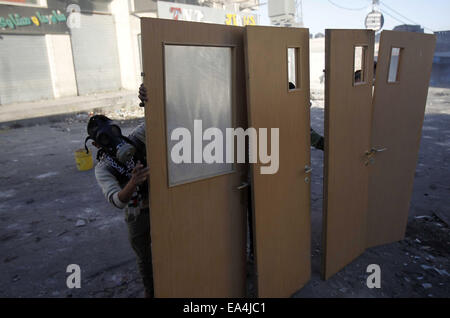 Jerusalem, Jerusalem, Palästina. 6. November 2014. Maskierte palästinensische Jugendliche benutzen Türen als Schild bei Zusammenstößen mit israelischen Sicherheitskräften in die palästinensischen Flüchtlingslager Schuafat in Ost-Jerusalem, am 6. November 2014. Israel hat keine Pläne, den Status Quo in Jerusalem Flashpoint Al-Aqsa Moschee zusammengesetzte ändern indem es jüdische Gebet es erlaubt, Premierminister Benjamin Netanyahu sagte Jordaniens König Abdullah II Credit: Muammar Awad/APA Bilder/ZUMA Draht/Alamy Live News Stockfoto