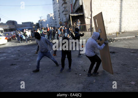 Jerusalem, Jerusalem, Palästina. 6. November 2014. Maskierte palästinensische Jugendliche benutzen Türen als Schild bei Zusammenstößen mit israelischen Sicherheitskräften in die palästinensischen Flüchtlingslager Schuafat in Ost-Jerusalem, am 6. November 2014. Israel hat keine Pläne, den Status Quo in Jerusalem Flashpoint Al-Aqsa Moschee zusammengesetzte ändern indem es jüdische Gebet es erlaubt, Premierminister Benjamin Netanyahu sagte Jordaniens König Abdullah II Credit: Muammar Awad/APA Bilder/ZUMA Draht/Alamy Live News Stockfoto