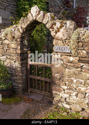 Alten Schiefer Stein Mauer mit Torbogen über Holztor in Garten Stockfoto