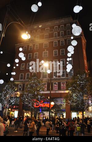 Shopper außen Oxford Street Disney Store mit Weihnachtsbeleuchtung in der Nacht, London Stockfoto