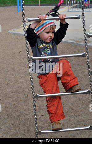 Ein kleiner Junge (2 1/2 Jahre) ein Aufstieg auf einem Klettergerüst Stockfoto