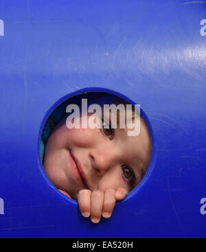 Ein kleiner Junge (2 1/2 Jahre alt) Blick durch ein Loch auf einem Spielplatz Klettern Spiel Stockfoto