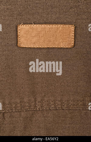 Leere Leder-Label-Tag auf Baumwolle Stoff Materialtextur Hintergrund. Stockfoto