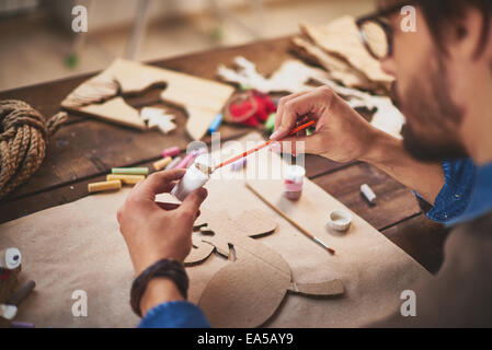 Nahaufnahme des Handwerkers Xmas Symbole mit weißen Gouache Malerei Stockfoto