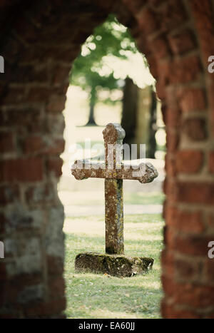 Alten Grabstein Kreuz gesehen durch Torbogen im Friedhof, Schweden Stockfoto