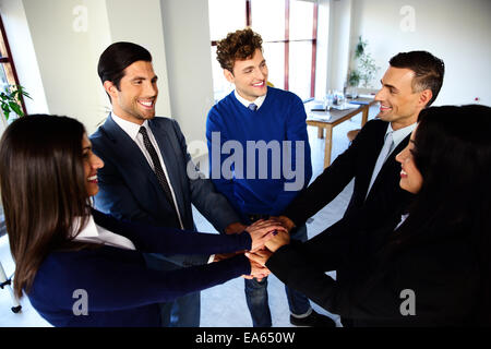 Glückliche Mitarbeiter machen Haufen von Händen und sahen einander Stockfoto