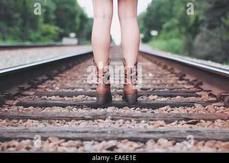 Teenager-Mädchen in Stiefeln stehen auf Bahngleisen Stockfoto