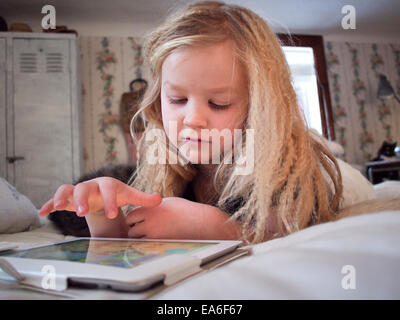 Mädchen auf Bett mit digital-Tablette Stockfoto