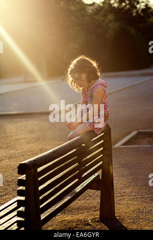 Mädchen sitzen auf der Rückseite von einer Holzbank Stockfoto