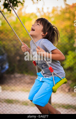 Junge lachend und schwingen auf einer Schaukel Stockfoto