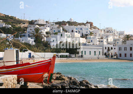 Mykonos-Stadt an einem schönen sonnigen Tag mit einem traditionellen roten gemalte hölzerne Angelboot/Fischerboot im Vordergrund, Kykladen, Griechenland. Stockfoto