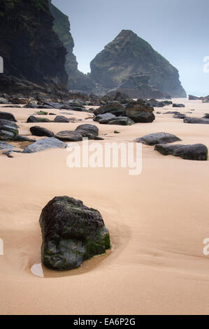 Sand und Felsen am Strand von Bedruthan Steps in Cornwall an einem launisch und bewölkten Tag. Stockfoto