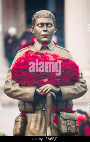 Trafalgar Square, London, UK. 7. November 2014. Die Royal British Legion vorgestellt, die jeder Mann erinnerte Skulptur auf dem Trafalgar Square, eine gemeinsame Stück mit dem Künstler Mark Humphrey. Die Messing-Skulptur, lose basierend auf der unbekannte Soldat, steht auf einem Sockel aus Kalkstein aus der Somme bezogen und ist eingehüllt in eine Plexiglas-Obelisk, umgeben von Mohn, die alle fünf Minuten, um die Figur herum schweben. Bild: Eingebettet in seine Arme, eine kostbare Last des Mohns. Bildnachweis: Paul Davey/Alamy Live-Nachrichten Stockfoto