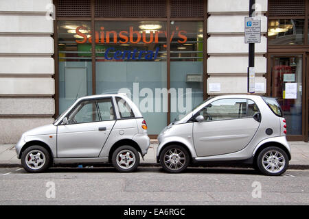 Zwei kleine Autos, eine elektrische und eine Benzin von verschiedenen Herstellern in einer einzigen Parkplatz in Mayfair London geparkt. Stockfoto