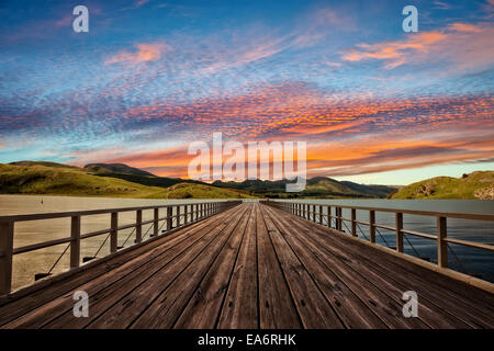 Schöne Landschaft am See mit Holzmole in den Bergen im Hintergrund. Stockfoto