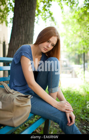 Trauriges Mädchen sitzt auf einer Parkbank Stockfoto