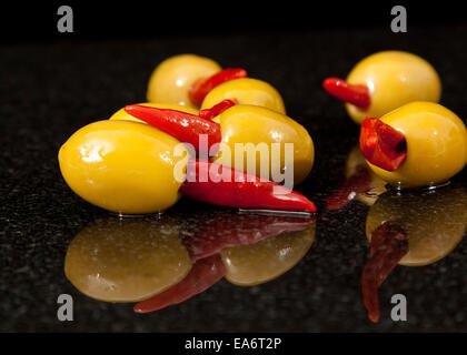 Rote Chili gefüllte Oliven in Olivenöl auf einem schwarzem Granit-Sockel Stockfoto