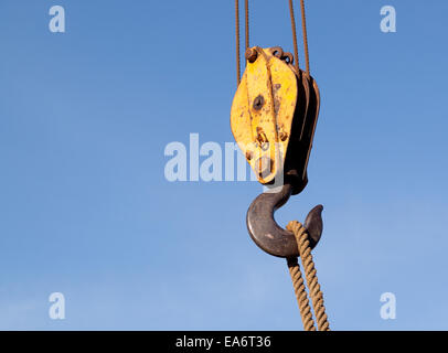 Nahaufnahme eines Kabels und Riemenscheibe und Haken an einem Kran auf einem Kran gegen einen klaren blauen Himmel heben ein Seil Stockfoto