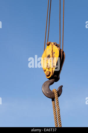 Nahaufnahme von Kabel- und Riemenscheibe und Haken auf einem Kran gegen einen klaren blauen Himmel heben ein Seil Stockfoto