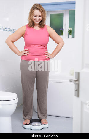 Glückliche Frau wiegen sich auf die Waage im Badezimmer Stockfoto