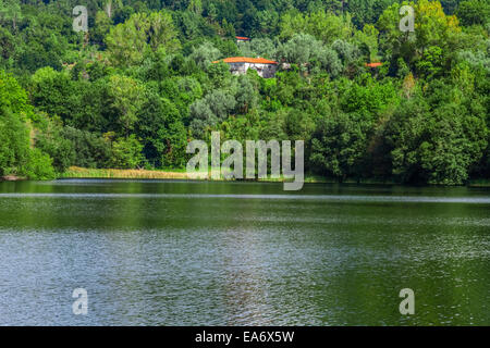 Traditionelles Steinhaus des Pontido Weilers spähen durch den Wald weiter den Queimadela Dam See. Fafe, Portugal Minho Stockfoto