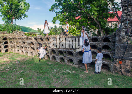 Sechs philippinische Kinder spielen an den Wänden der alten spanischen Kapelle, bekannt als die Ruinen der Ermita auf Bohol Island, Philippinen. Stockfoto