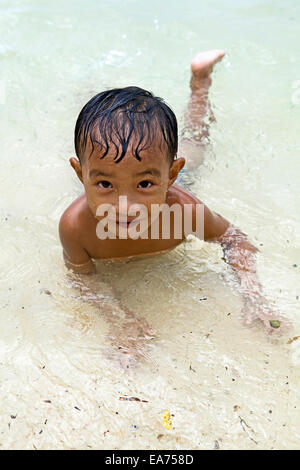 Ein Filipino junge etwa drei Jahre alt spielt in das seichte Wasser am Strand auf Guimaras Island, Philippinen...