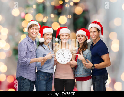 Gruppe von Jugendlichen in Santa Helfer Hüte mit Uhr Stockfoto