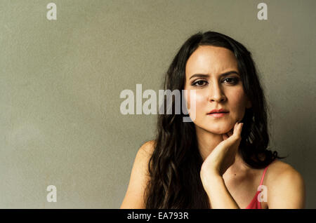 Studioportrait von Brünette junge Frau mit Hand am Kinn Stockfoto