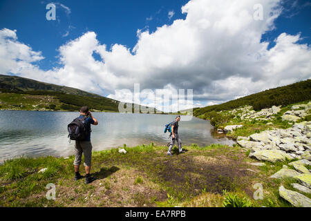 Zwei kaukasische Wanderer mit Rucksack wandern rund um einen See in den Bergen